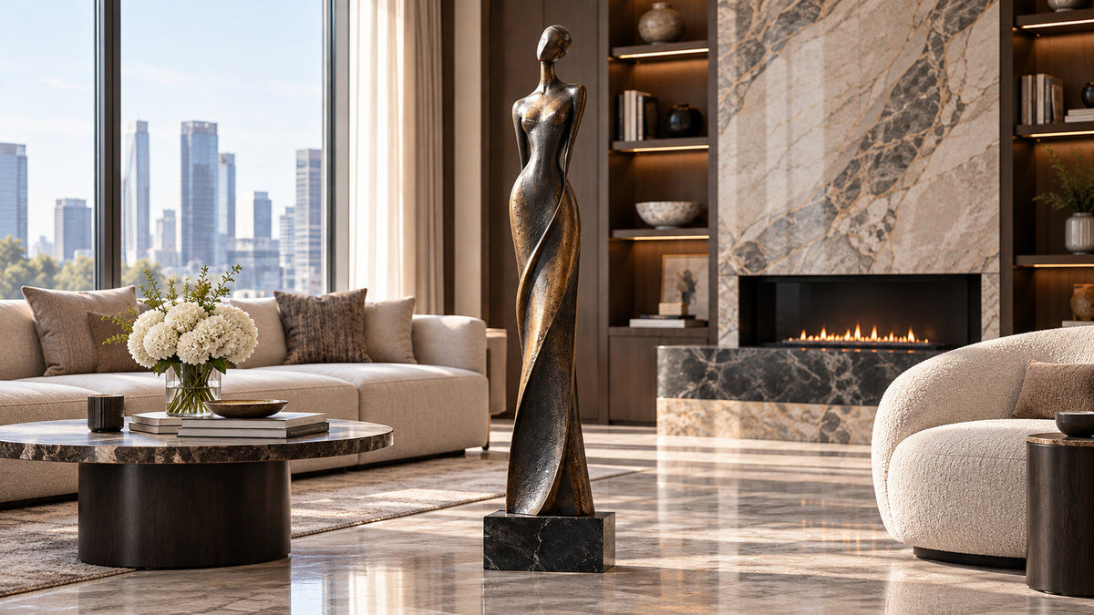 Slender bronze figure sculpture on a black marble pedestal in an elegant residential living room.