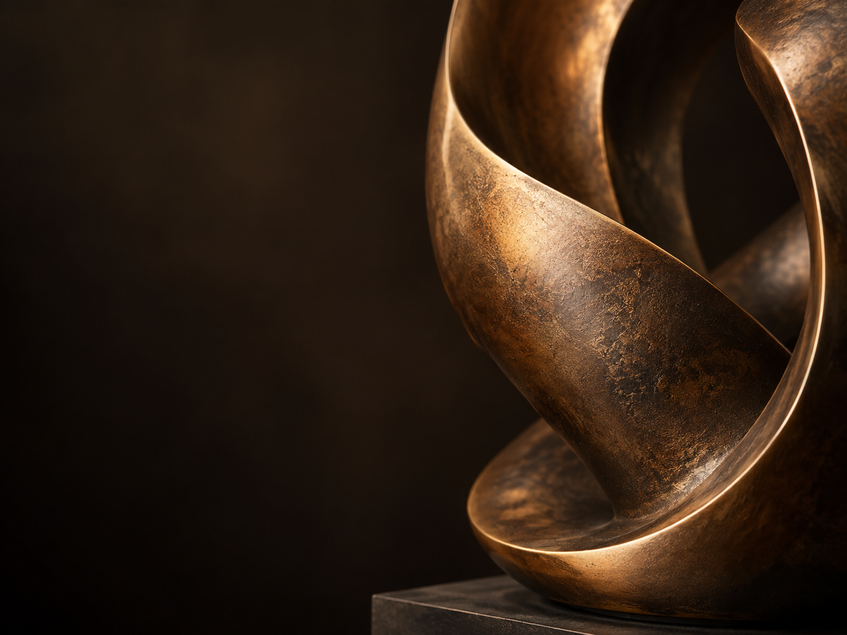 Close-up detail of a bronze abstract sculpture showing flowing curved forms, warm patina tones, and textured metal surface.