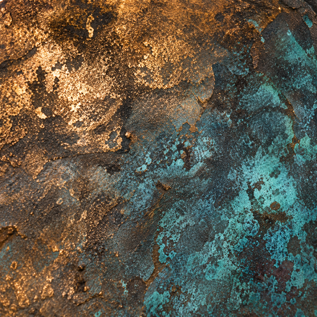 Detailed bronze surface with warm brown tones, blue-green oxidation, and layered patina texture.
