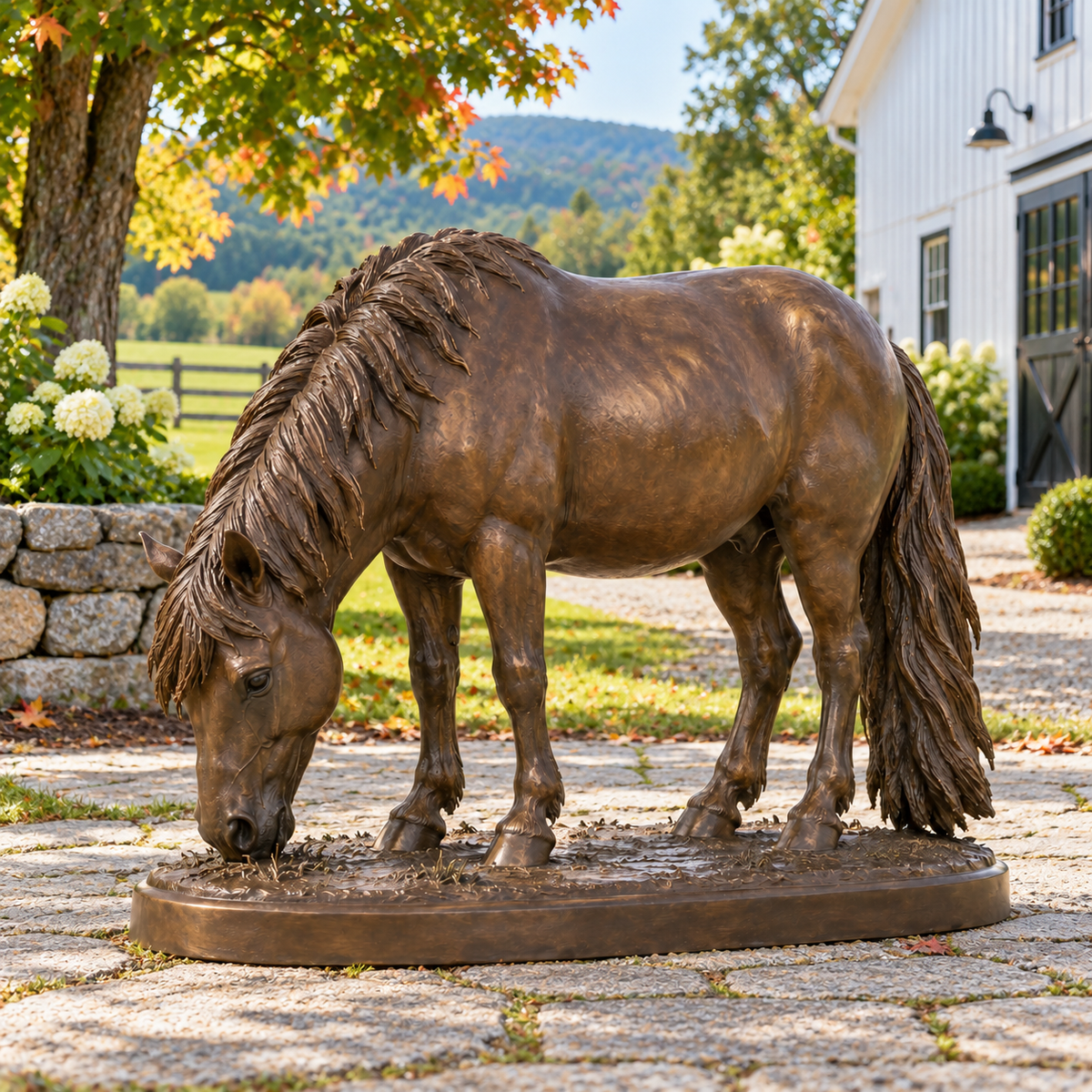 Copper Graze, warm bronze grazing pony sculpture, side view in Vermont farm granite path maples white barn