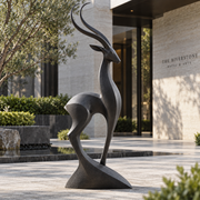 Desert Grace bronze abstract gazelle sculpture displayed outdoors at a contemporary hotel entrance courtyard.
