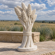 Harvest of Memory, white marble wheat sheaf memorial sculpture in a natural-light setting.