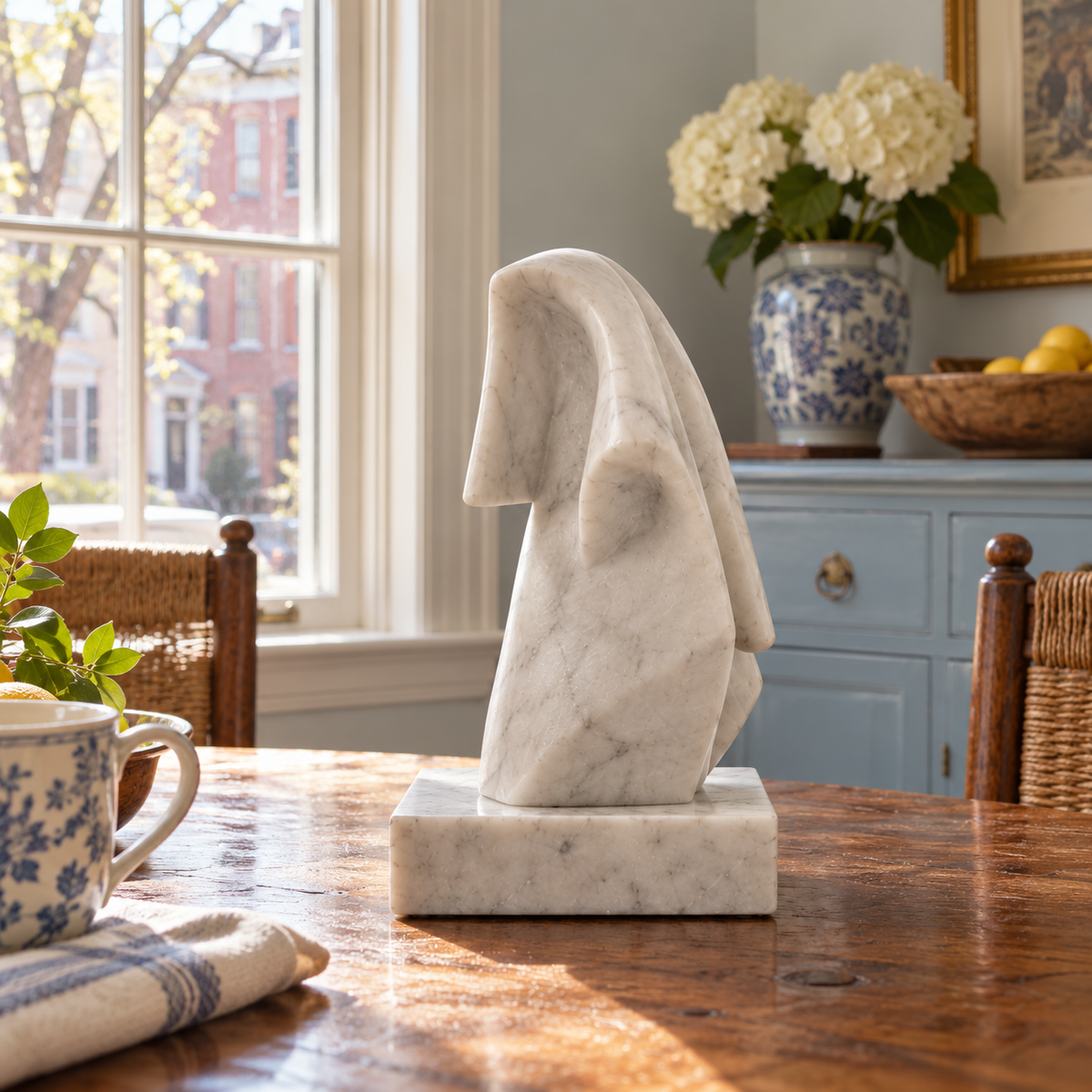 Side profile of Linen Afterlight white marble abstract draped fold sculpture in a different architectural or garden setting.