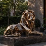 Regal Rest large bronze finish stainless steel geometric reclining lion sculpture displayed in a modern commercial landscape setting